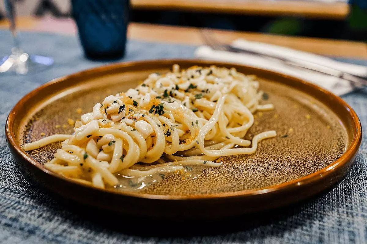 Piatto di spaghetti con le vongole e bottarga, ben presentato su un piatto