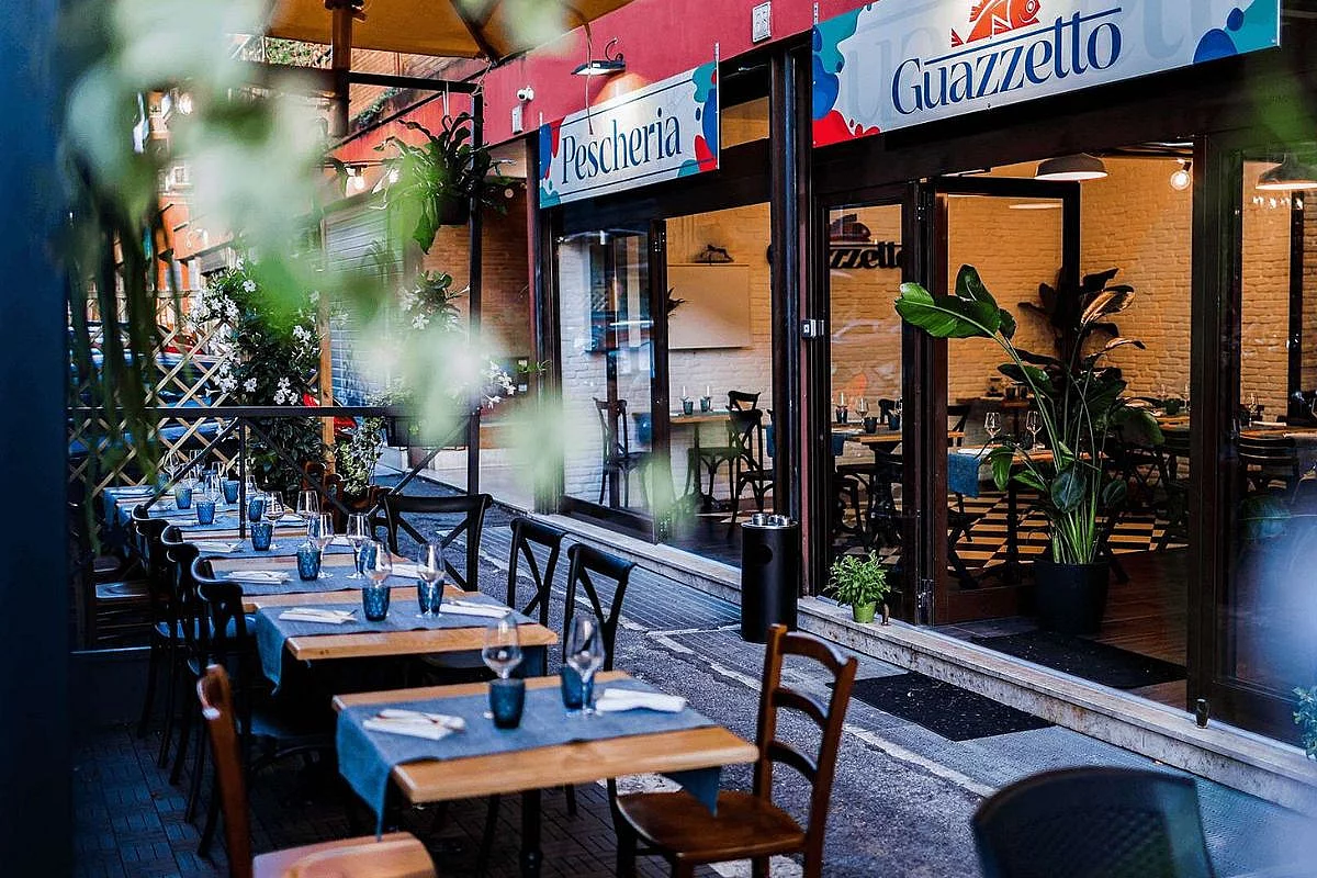 Veduta esterna con i tavoli di un ristorante di pesce a Roma, chiamato Guazzetto