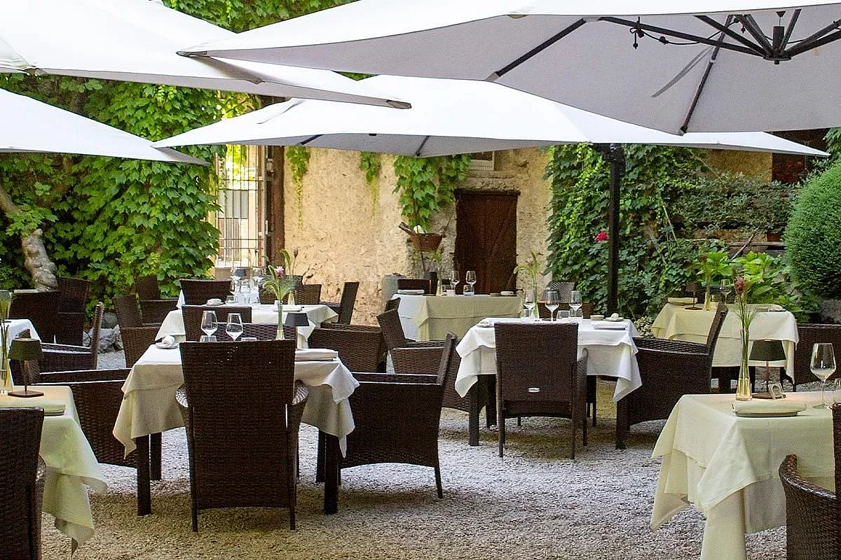 Immagine del ristorante La Corte degli Dei, che mostra i tavoli apparecchiati con gli ombrelloni da ristorante