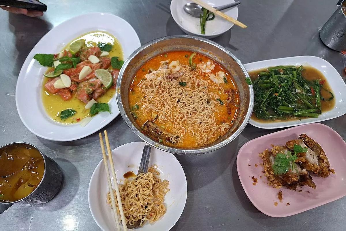 Menù di un ristorante di Bangkok, con un piatto di tagliolini istantanei in brodo piccante pieno di altri ingredienti come gamberi e polpette di suino