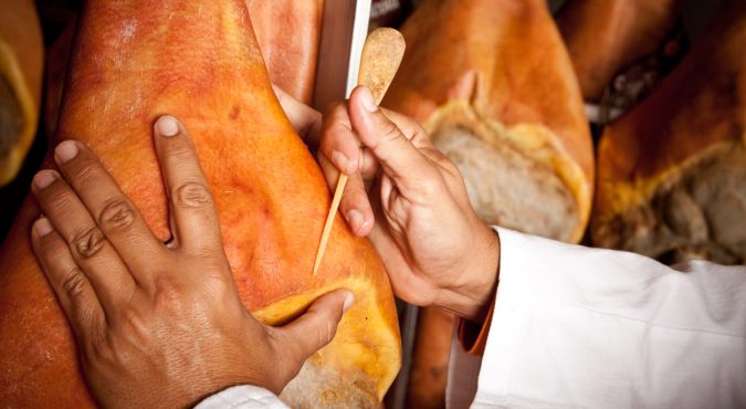 An inspector checking drying Parma ham
