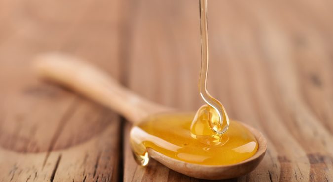 Honey dripping on a wooden spoon