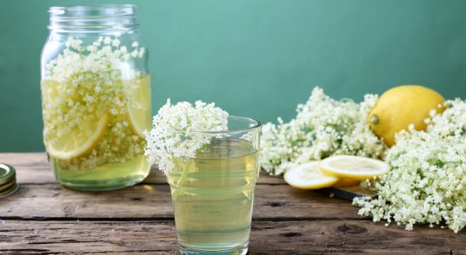 elderflower drink in glass green background