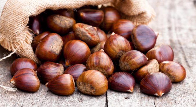fresh chestnuts in sack bag on the old wooden table